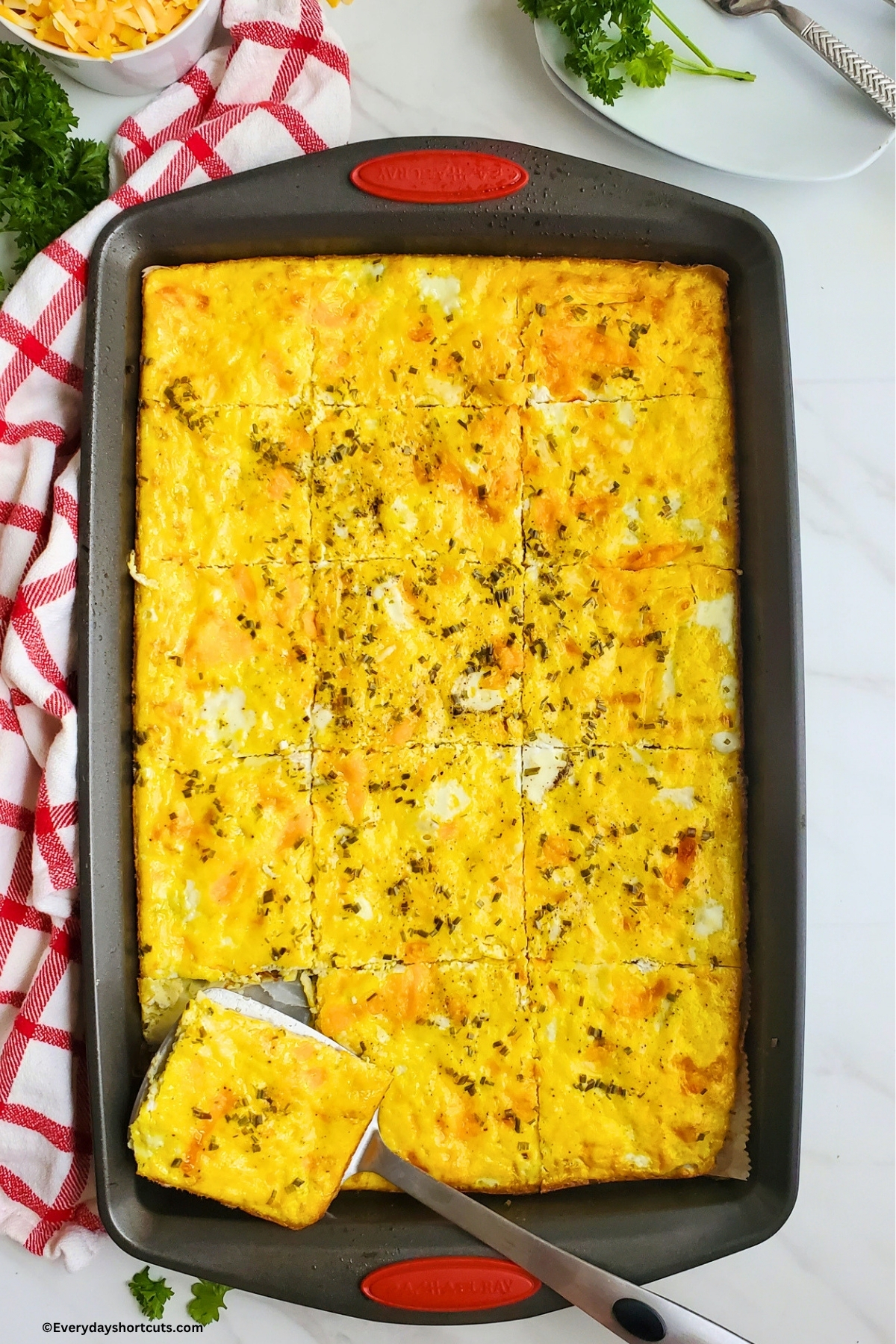 sheet pan eggs cut into squares on a baking dish next to a red and white striped napkin