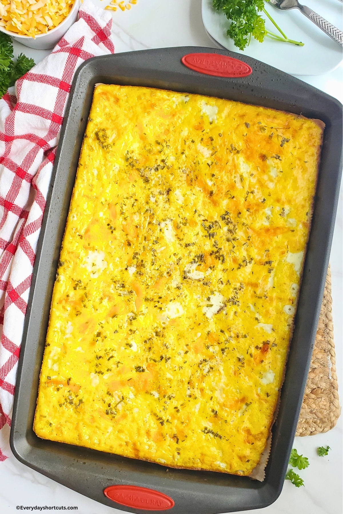 scrambled eggs baked on a sheet pan into one long rectangle next to a red and white striped napkin