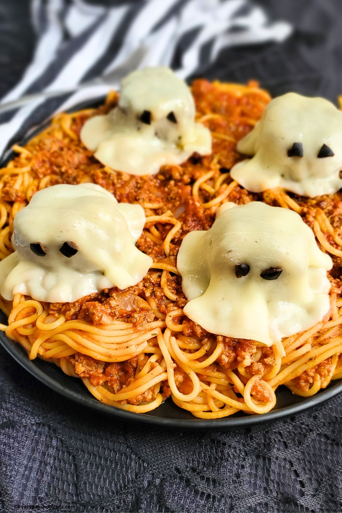 a plate of spaghetti with meatball ghosts on top