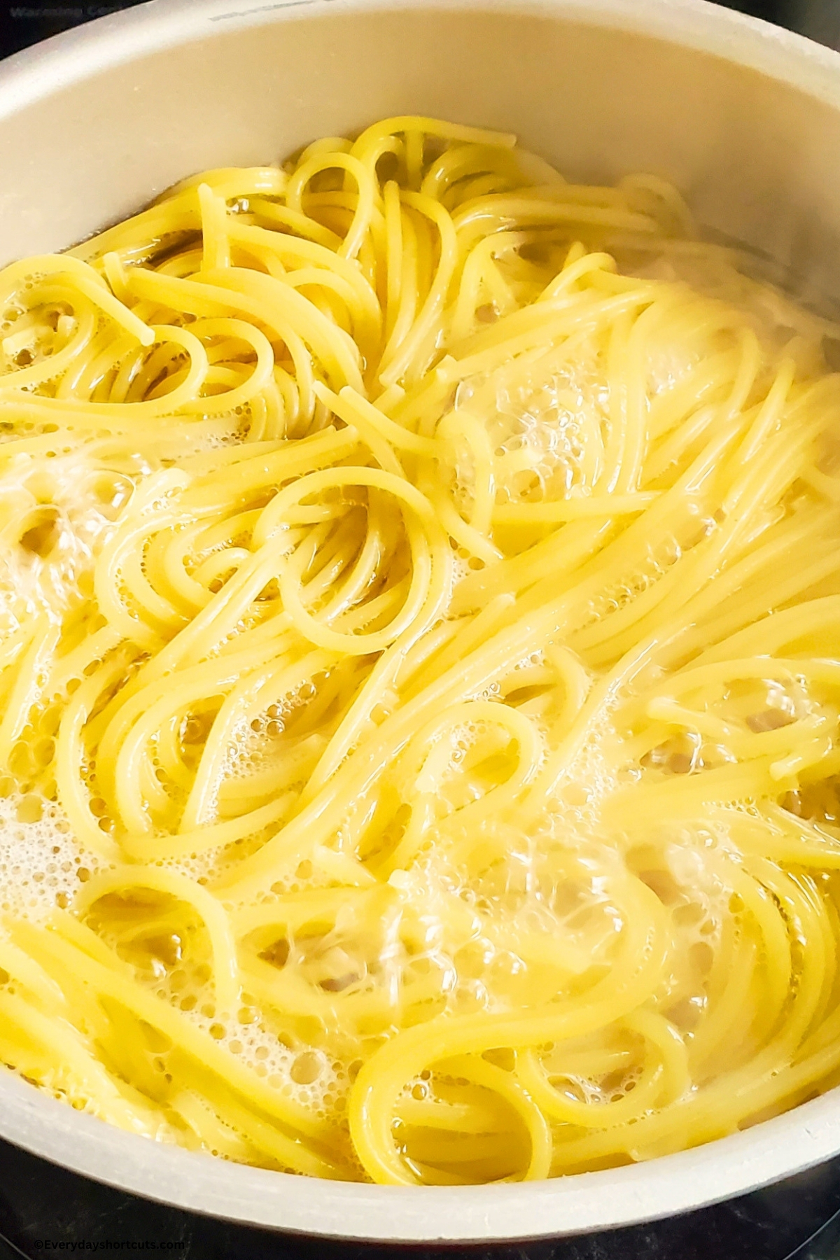 spaghetti noodles cooking in a pan