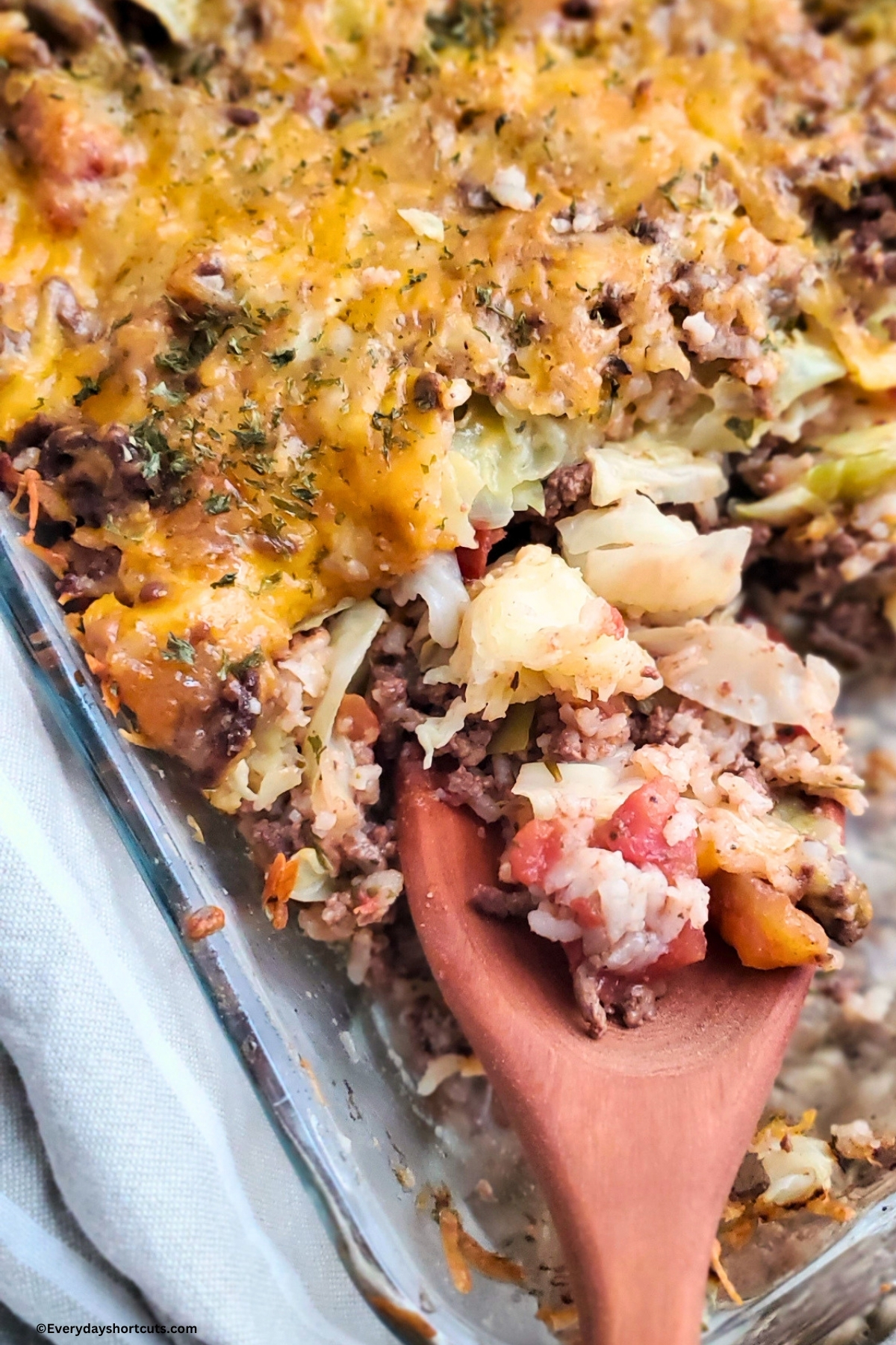 scoop of cabbage roll casserole on a wooden spoon in a baking dish