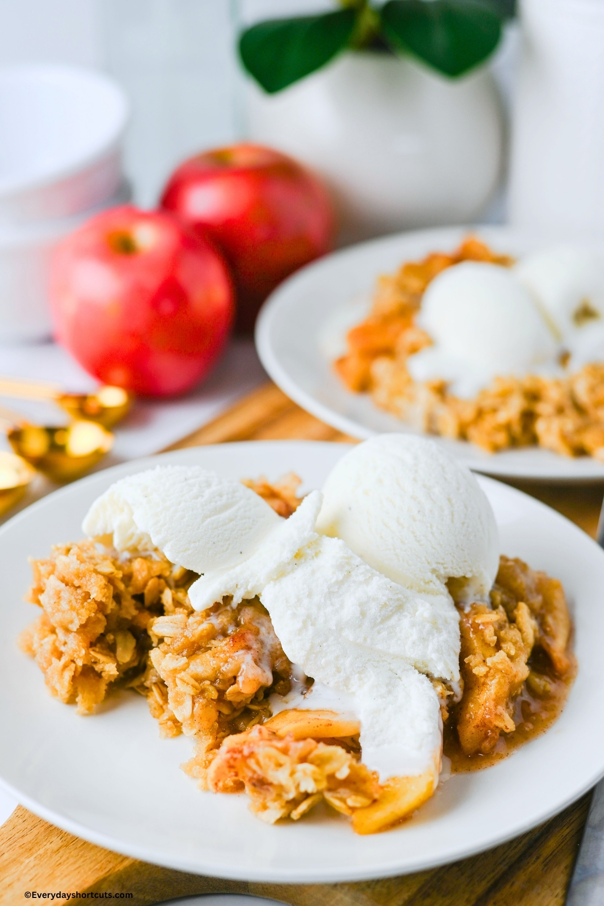 apple crisp on a white plate with a scoop of vanilla ice cream on top
