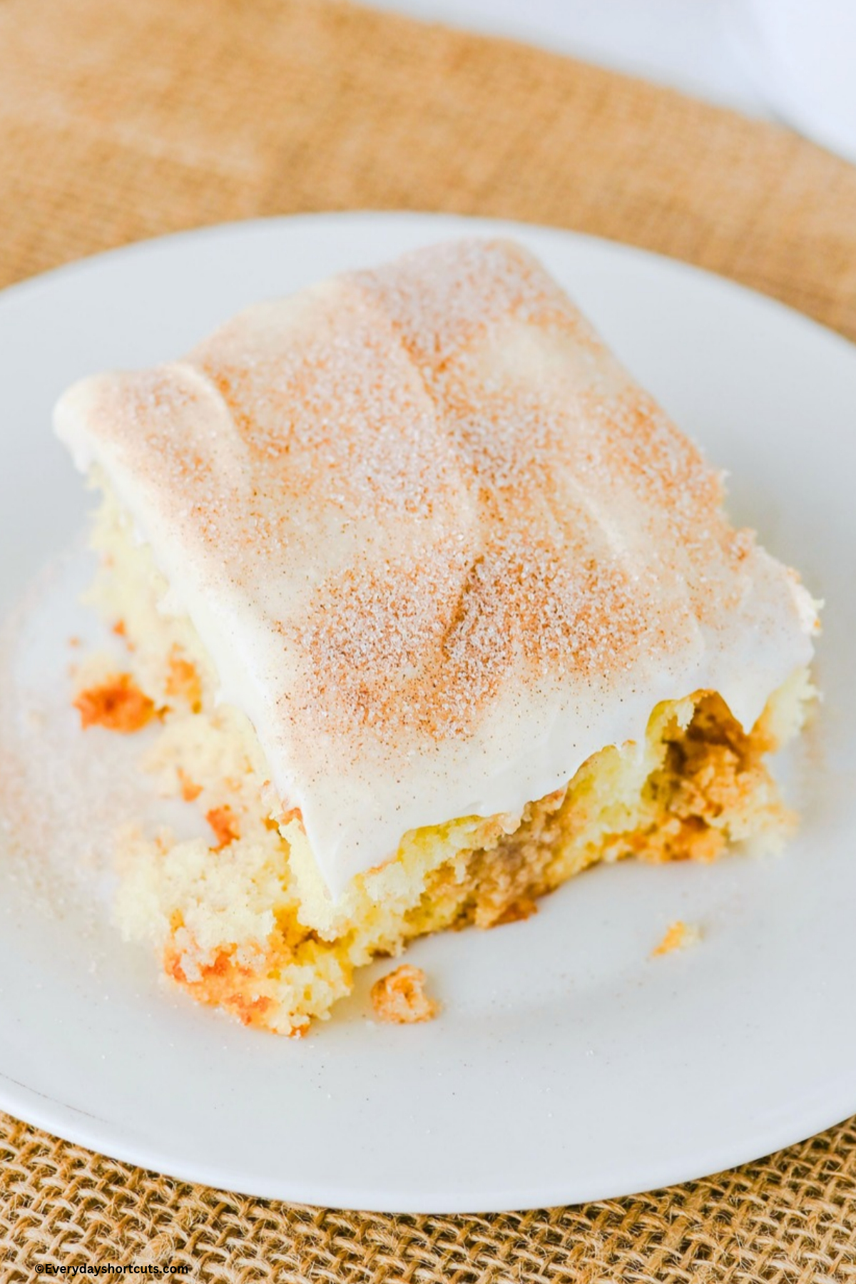 slice of cinnamon poke cake with frosting on a white plate
