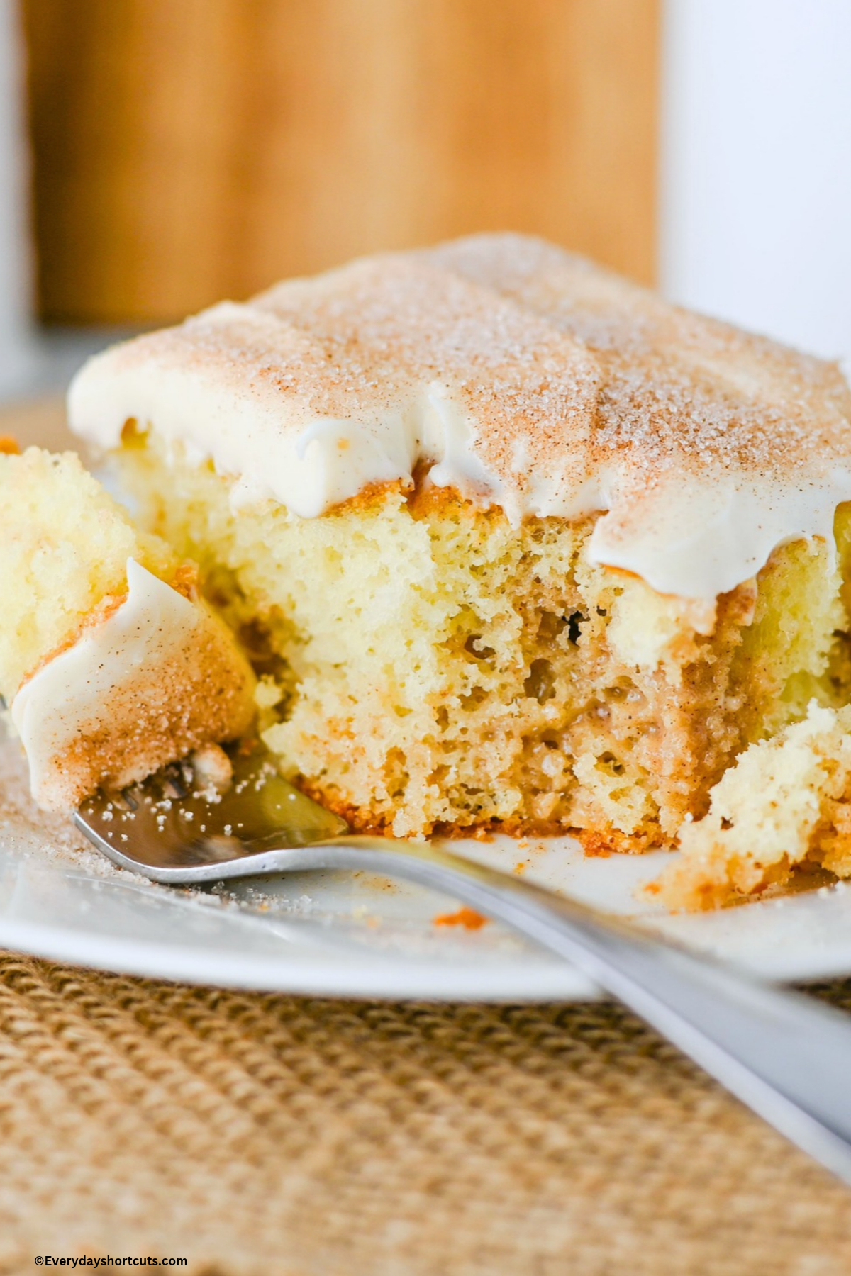piece of cinnamon roll poke cake on a fork next to a slice