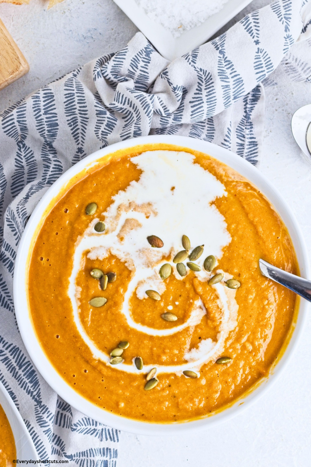 over top view of creamy pumpkin soup with heavy cream and pumpkin seeds drizzled over top