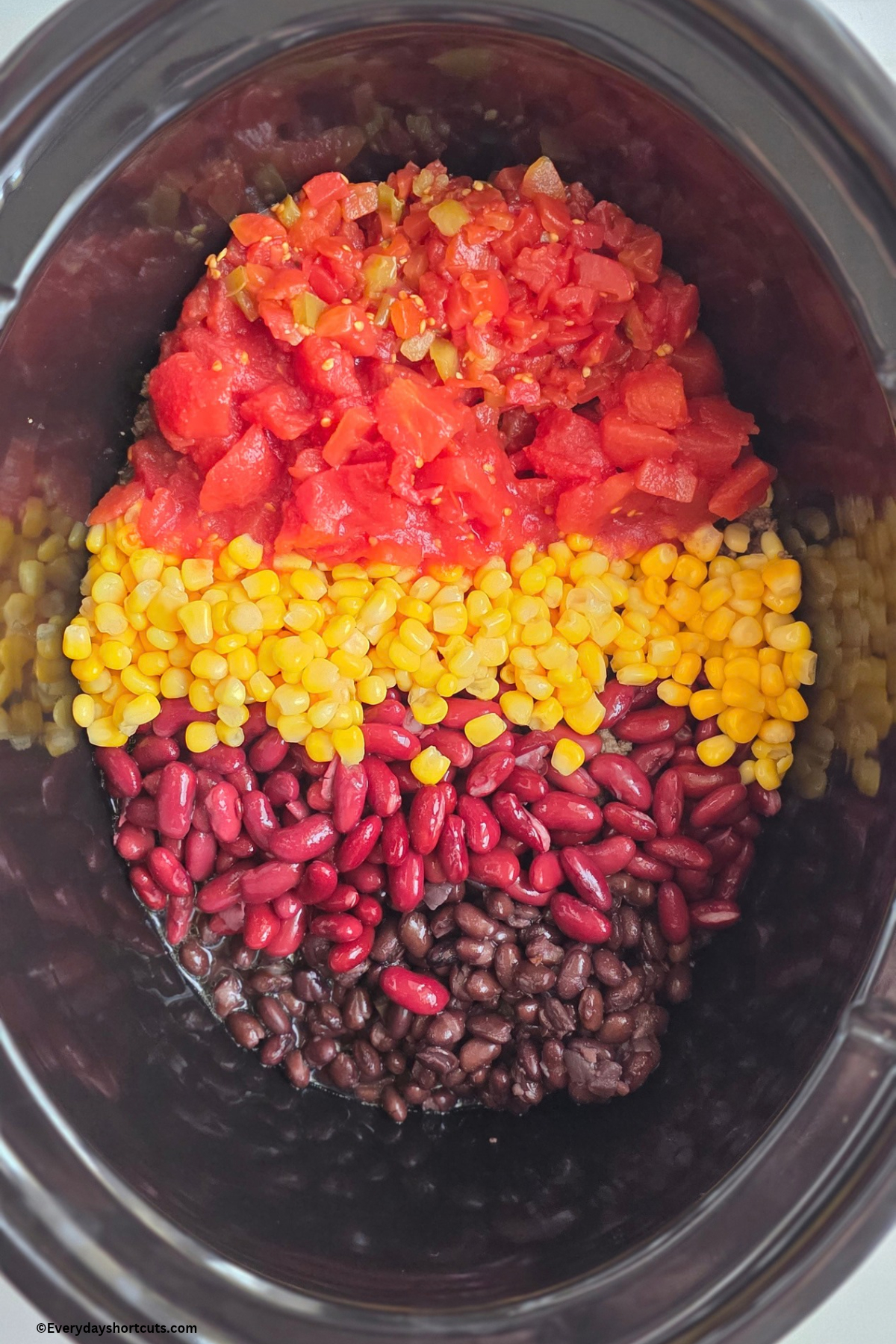 black beans, kidney beans, corn, diced tomatoes, diced tomatoes with green chilies on top of browned ground beef and onions in crock pot