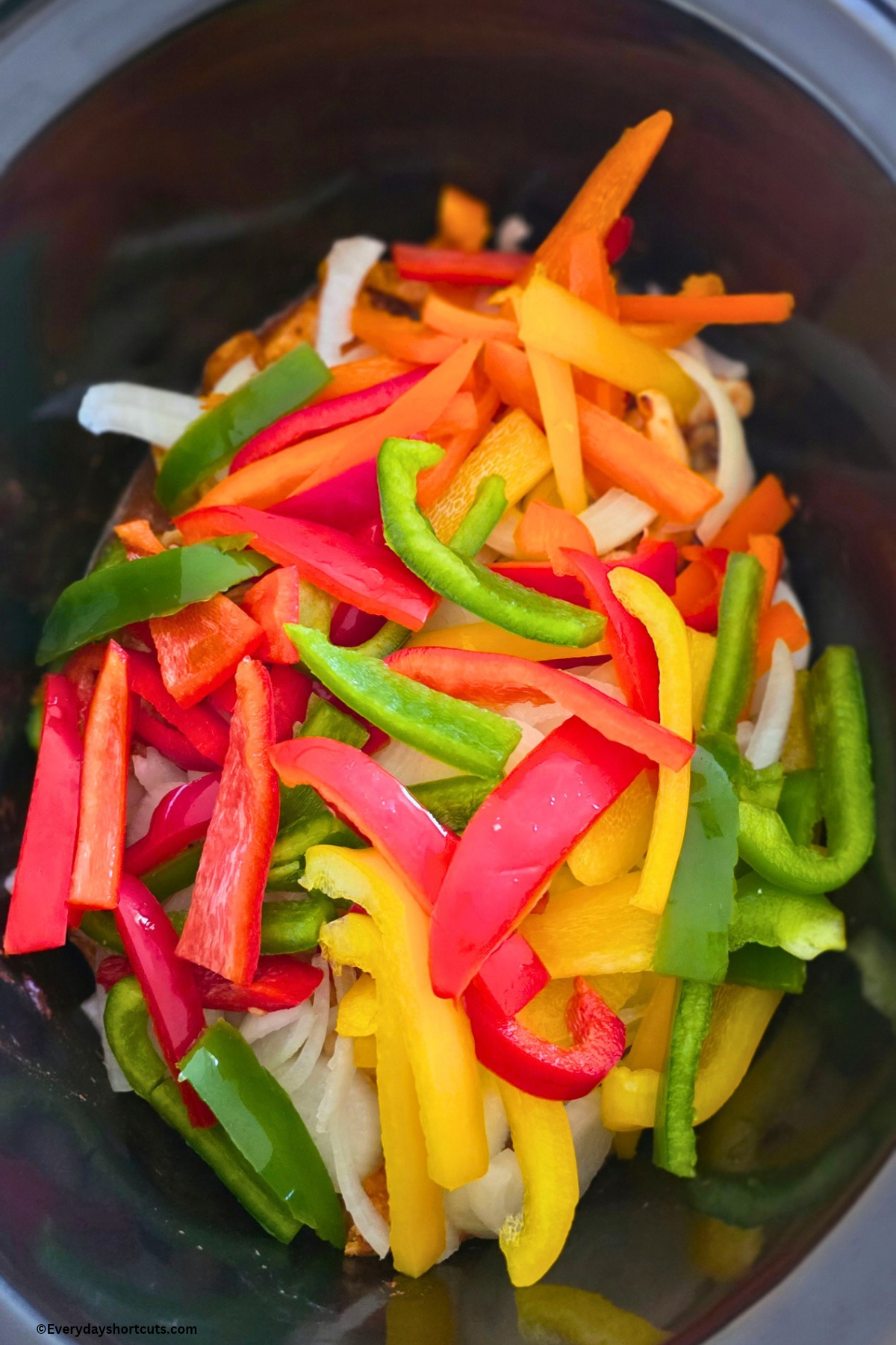 bell peppers and onions on top of chicken, salsa and fajita seasoning in crockpot