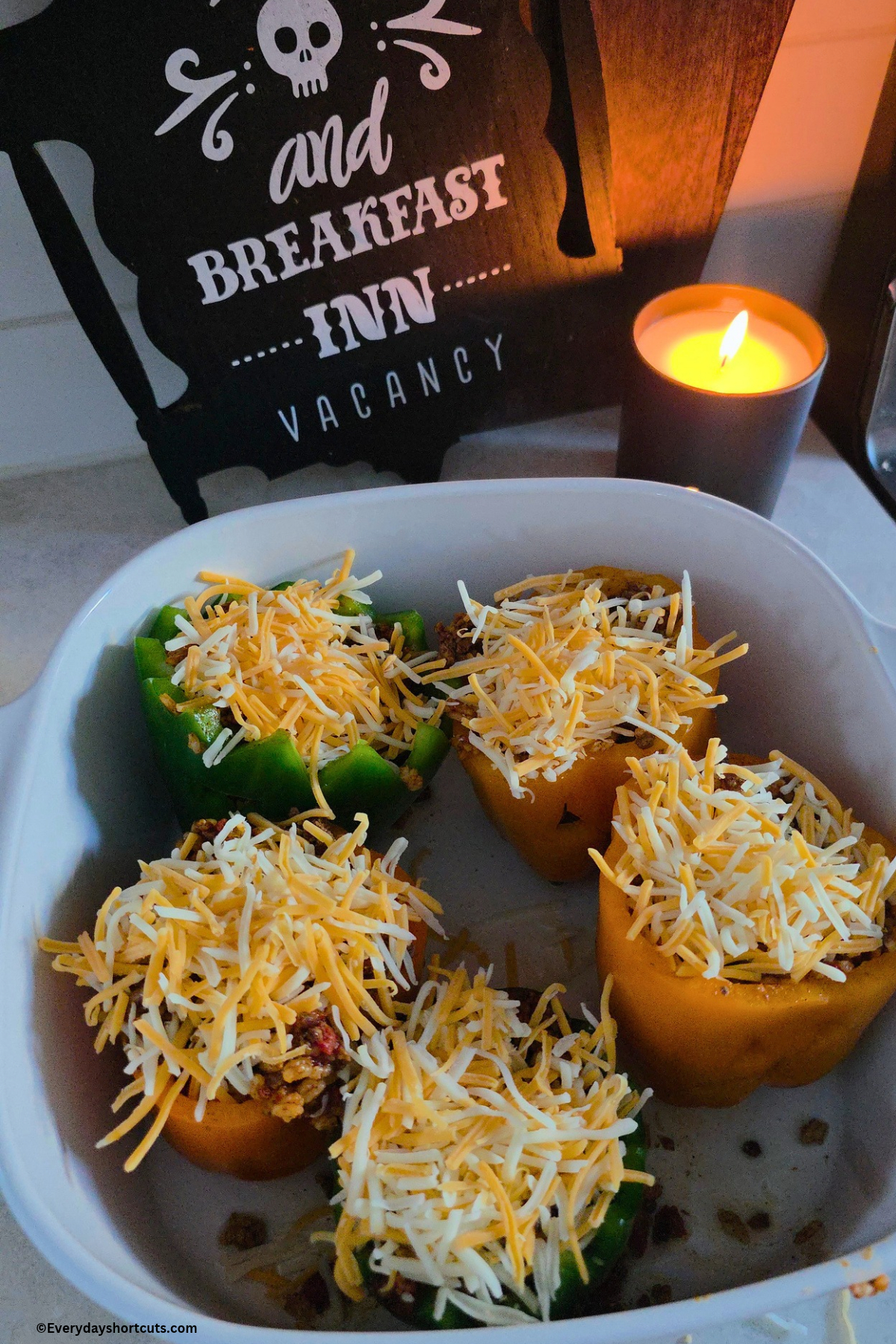 stuffed peppers in a white baking dish with shredded cheese on top