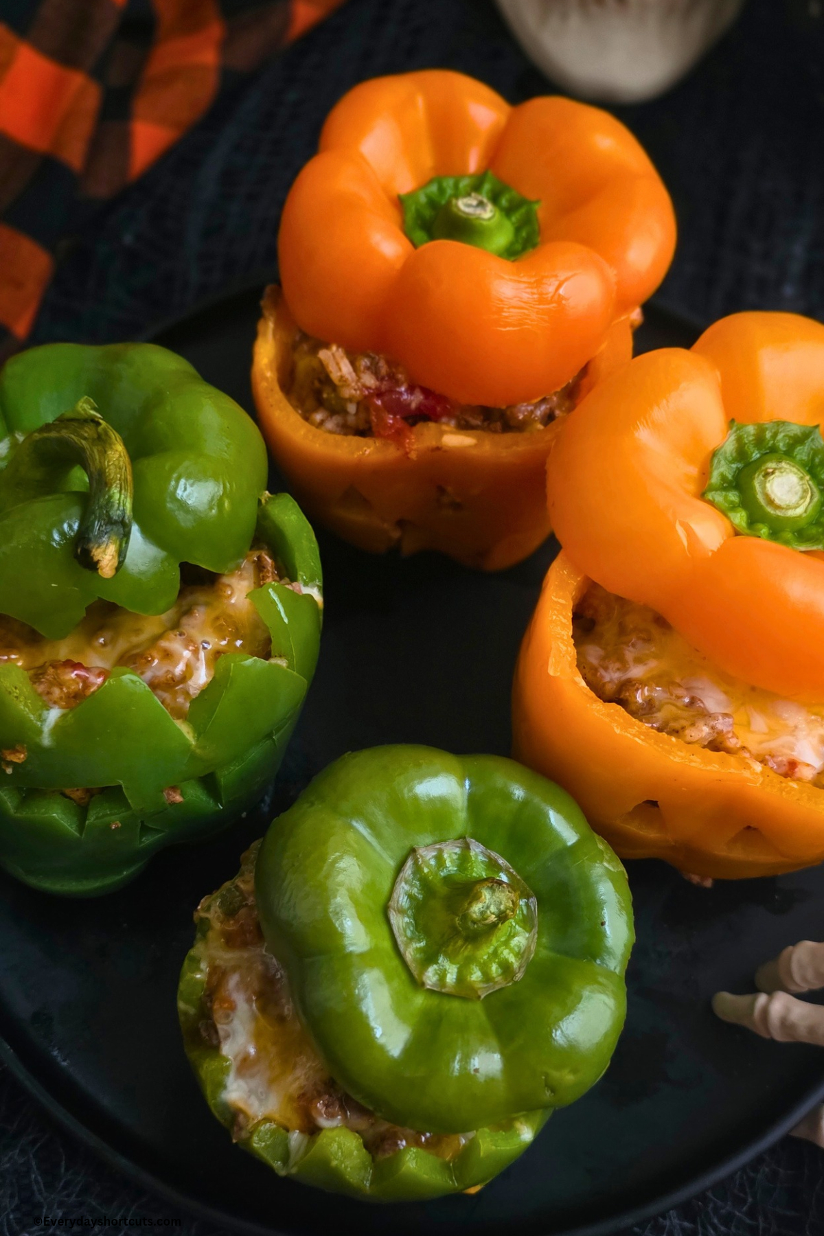 cooked stuffed peppers on a black plate and their tops slightly off